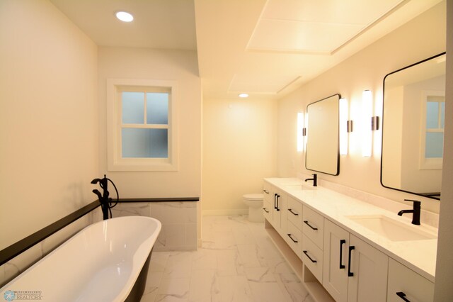 bathroom with toilet, vanity, and a tub to relax in