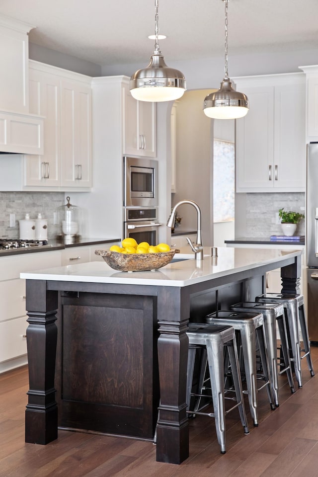 kitchen with decorative backsplash, dark hardwood / wood-style floors, and an island with sink