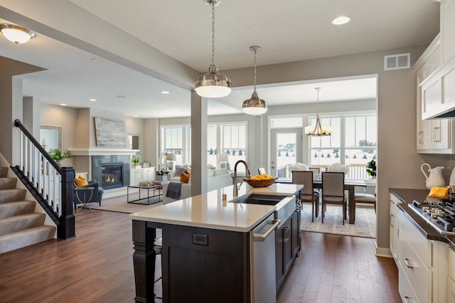 kitchen with white cabinetry, dark hardwood / wood-style flooring, appliances with stainless steel finishes, sink, and a center island with sink