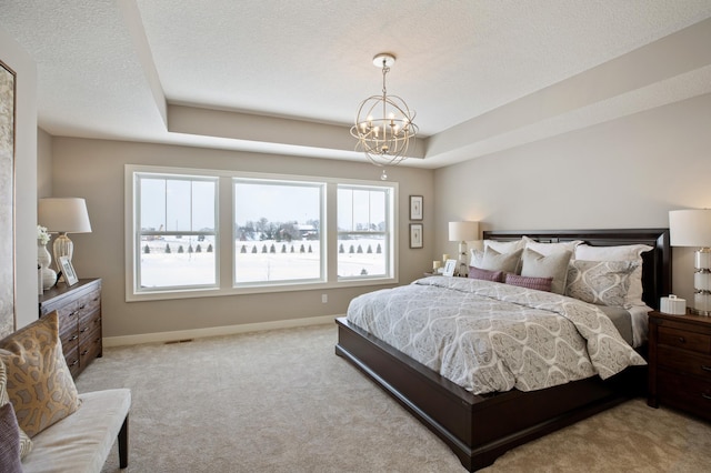 carpeted bedroom with an inviting chandelier, multiple windows, and a tray ceiling