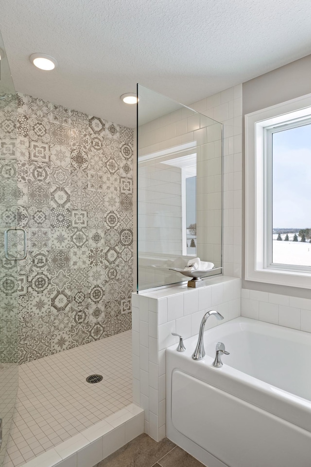 bathroom featuring a textured ceiling, tile patterned flooring, and separate shower and tub