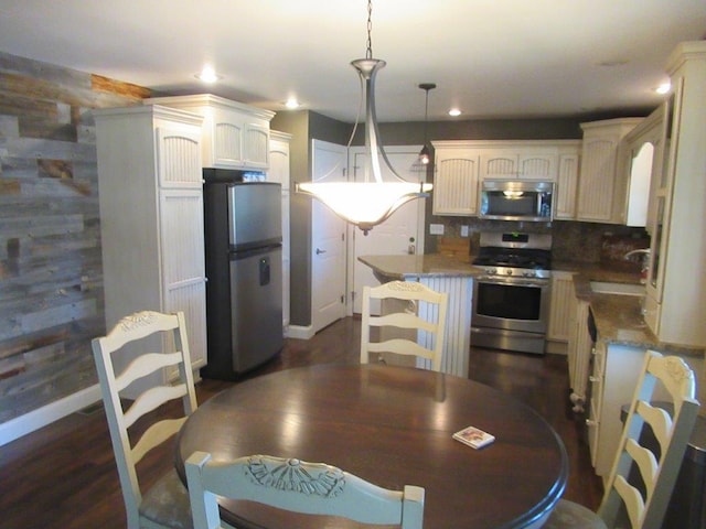 kitchen featuring decorative backsplash, dark hardwood / wood-style flooring, stainless steel appliances, sink, and hanging light fixtures