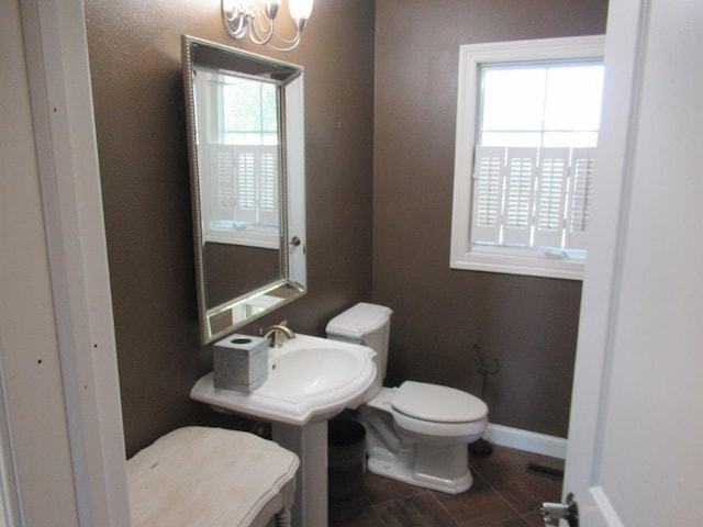 bathroom with a chandelier, toilet, and a wealth of natural light