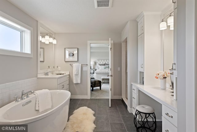 bathroom with a textured ceiling, tile flooring, a bathing tub, and vanity