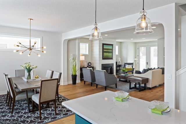 dining space featuring hardwood / wood-style floors, a notable chandelier, a fireplace, and a textured ceiling