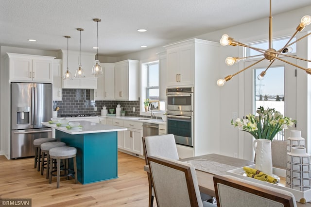 kitchen with white cabinets, a kitchen island, pendant lighting, and appliances with stainless steel finishes