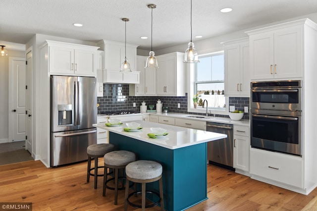 kitchen featuring a center island, white cabinets, stainless steel appliances, and light wood-type flooring