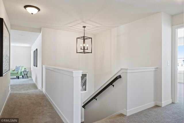 corridor with light carpet and a notable chandelier