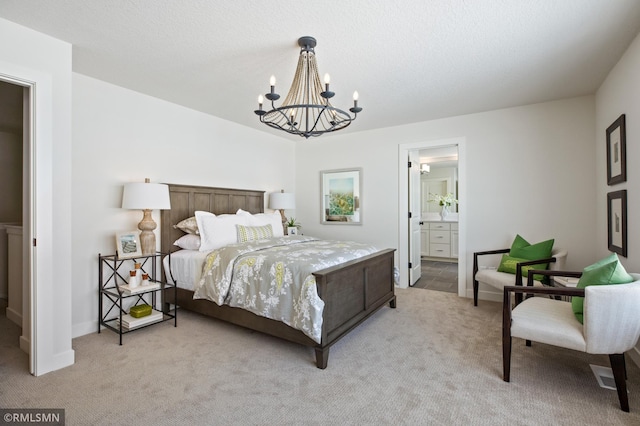 carpeted bedroom with ensuite bathroom, a textured ceiling, and an inviting chandelier