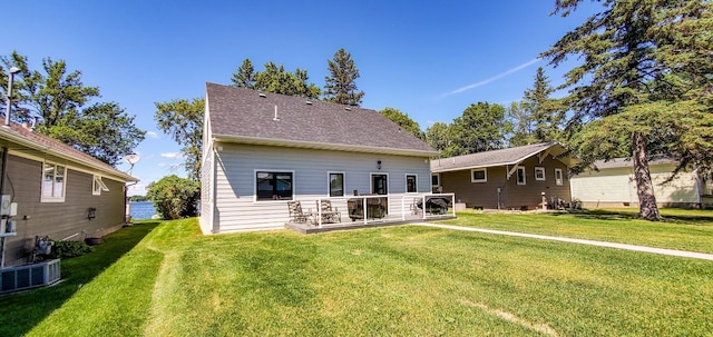 rear view of house featuring central air condition unit, a yard, and roof with shingles