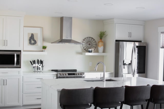 kitchen with a sink, light stone counters, appliances with stainless steel finishes, wall chimney exhaust hood, and open shelves