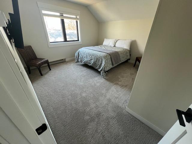 carpeted bedroom featuring baseboards and vaulted ceiling