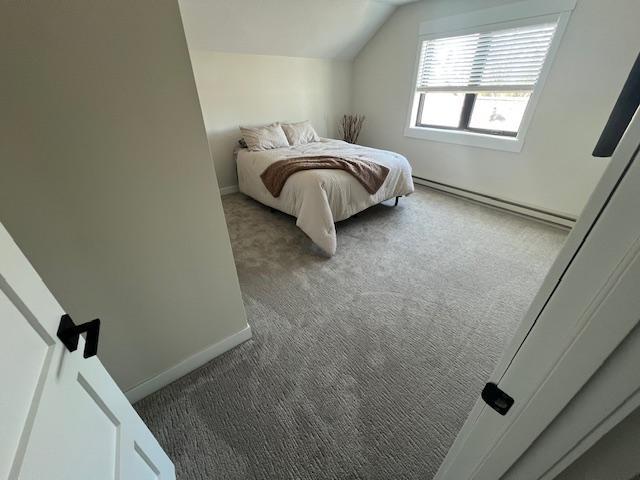 carpeted bedroom with baseboards, lofted ceiling, and a baseboard radiator