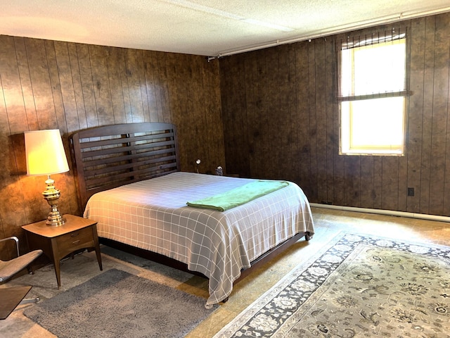 bedroom featuring a textured ceiling and wooden walls