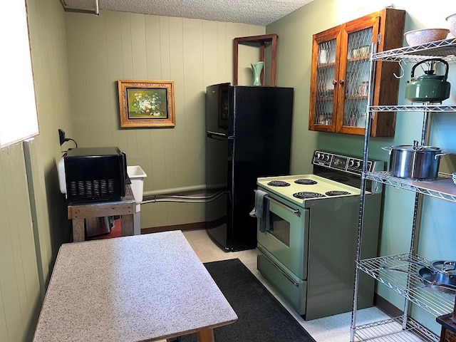 kitchen featuring black refrigerator, a textured ceiling, and electric range