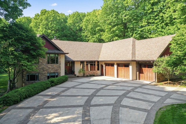 split level home featuring a garage, a shingled roof, stone siding, and concrete driveway