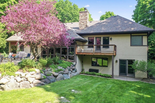 rear view of property featuring a lawn and a balcony