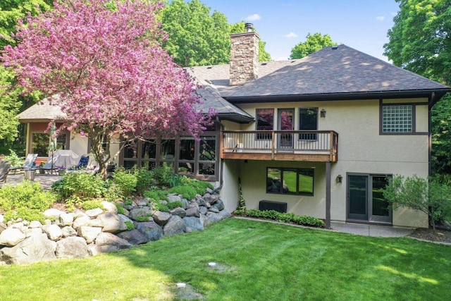 rear view of house featuring stucco siding, a chimney, and a yard