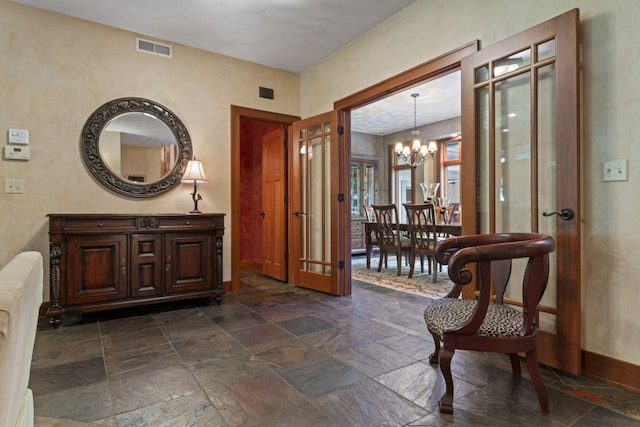 interior space featuring stone tile floors, an inviting chandelier, visible vents, french doors, and baseboards