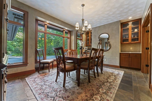 dining area with a chandelier, stone tile floors, and baseboards