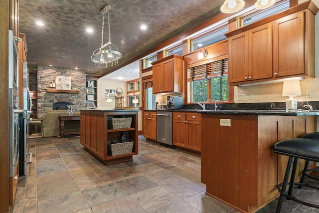 kitchen featuring a fireplace, a kitchen breakfast bar, kitchen peninsula, and hanging light fixtures