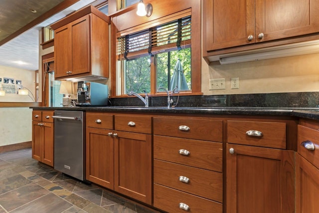 kitchen with dark stone counters, brown cabinets, baseboards, and stone tile flooring