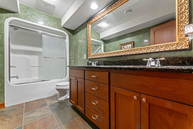 full bath featuring a sink, double vanity, toilet, stone finish flooring, and enclosed tub / shower combo