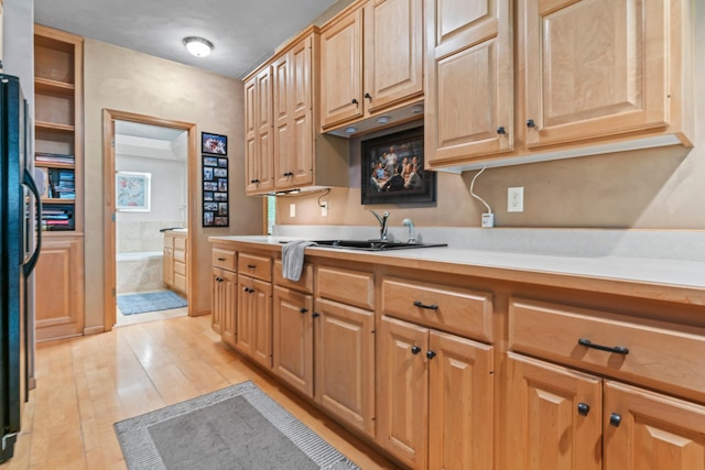 kitchen with a sink, light brown cabinetry, light wood-style floors, light countertops, and freestanding refrigerator