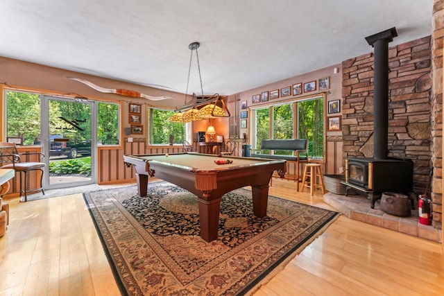 playroom with wood-type flooring, a wood stove, and billiards