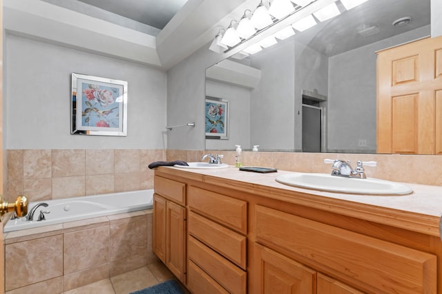 bathroom with tile patterned flooring, vanity, and a relaxing tiled tub