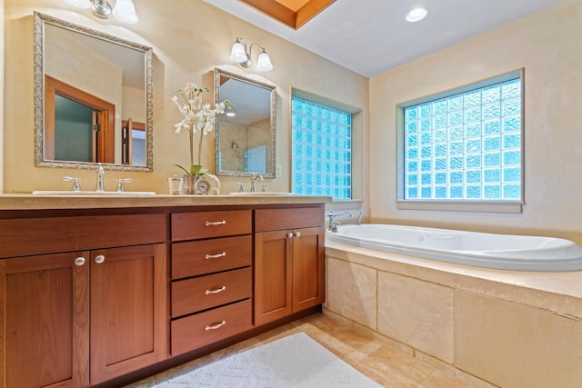 bathroom with tile patterned floors, a relaxing tiled tub, and vanity