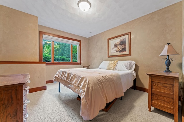 bedroom featuring a textured ceiling and light colored carpet