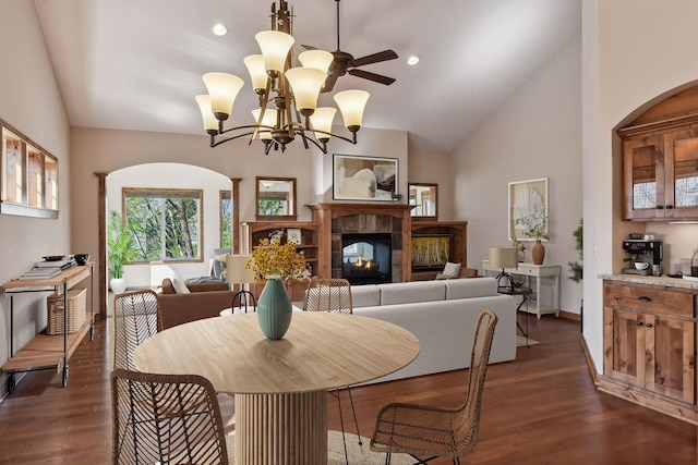 dining area with a tiled fireplace, dark wood-style floors, recessed lighting, ceiling fan with notable chandelier, and lofted ceiling
