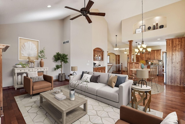 living area featuring ceiling fan with notable chandelier, high vaulted ceiling, arched walkways, light wood-type flooring, and visible vents