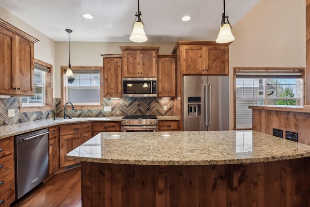 kitchen featuring backsplash, brown cabinetry, a sink, premium appliances, and dark wood-style floors