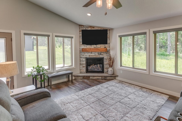 living room featuring ceiling fan, a fireplace, wood-type flooring, and vaulted ceiling