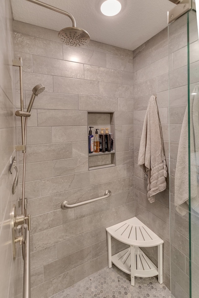 bathroom with tiled shower, a textured ceiling, and tile patterned flooring