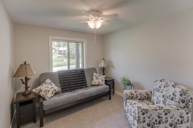 living room with a textured ceiling, ceiling fan, and light carpet