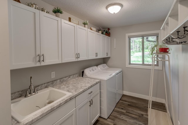 laundry room with sink, cabinets, dark hardwood / wood-style floors, independent washer and dryer, and a textured ceiling