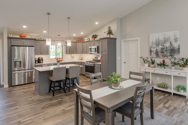 dining area featuring sink, high vaulted ceiling, and hardwood / wood-style flooring