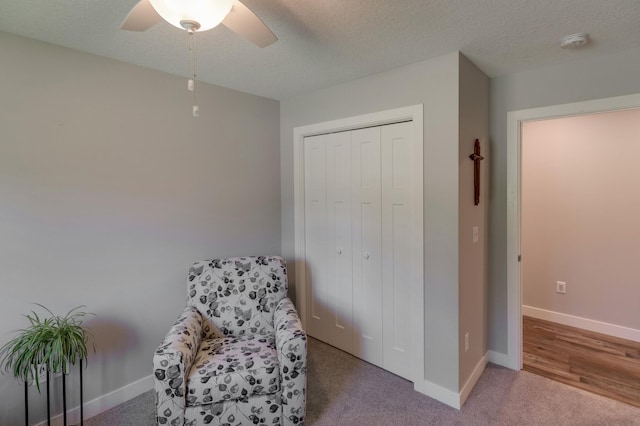 sitting room with ceiling fan, carpet, and a textured ceiling