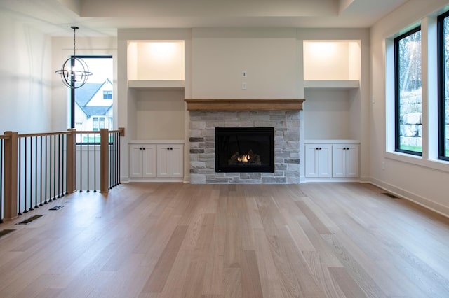 unfurnished living room with built in shelves, a healthy amount of sunlight, and light hardwood / wood-style floors