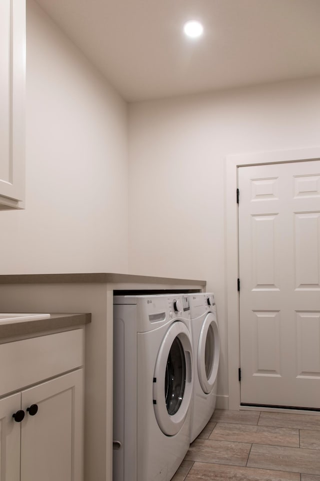 laundry area with washer and dryer, light hardwood / wood-style floors, and cabinets