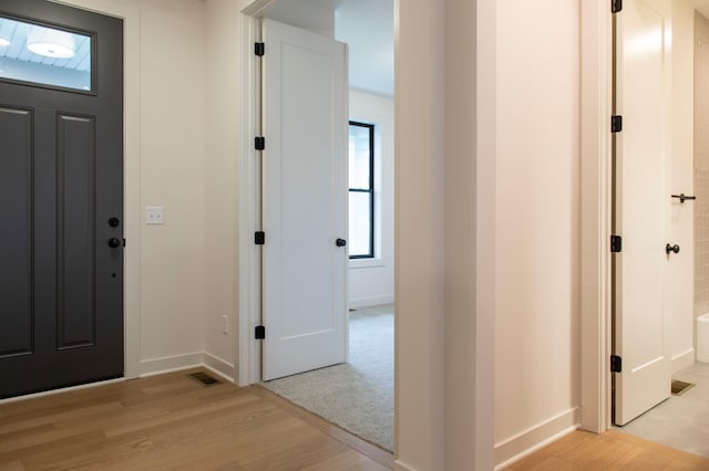 foyer with light wood-type flooring, visible vents, and baseboards