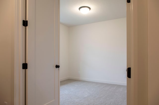 unfurnished room featuring baseboards and light colored carpet