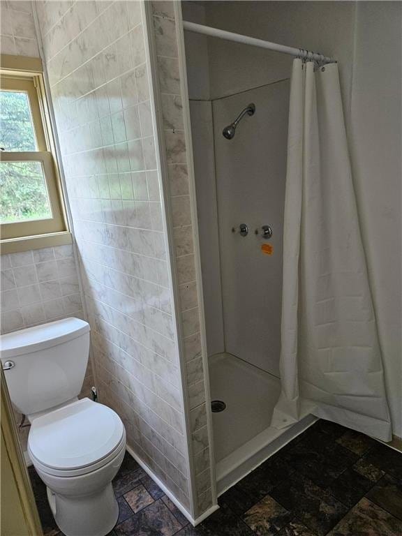 bathroom with a shower with shower curtain, toilet, and tile walls