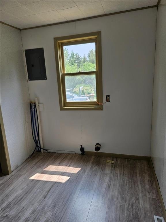 unfurnished room with electric panel and hardwood / wood-style floors