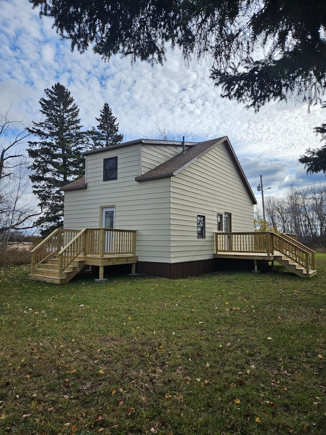 rear view of house featuring a lawn and a wooden deck