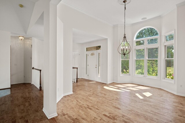 unfurnished dining area with hardwood / wood-style floors, a chandelier, ornamental molding, and a healthy amount of sunlight