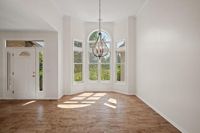 foyer entrance featuring hardwood / wood-style floors, an inviting chandelier, ornamental molding, and a healthy amount of sunlight